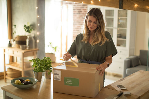 Frau öffnet Paket mit Aufdruck