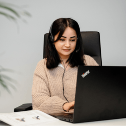 Kundenserviceberaterin von enviropack.de sitzt am Arbeitstisch mit Laptop und Headset